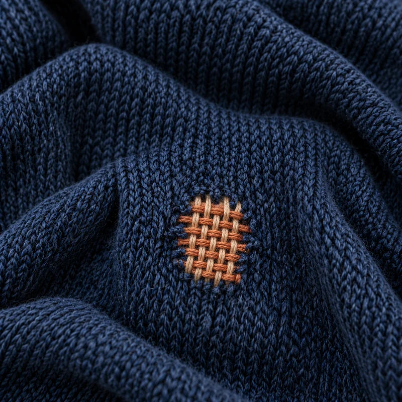Reprise tissée orange et écrue dans une maille bleu marine.