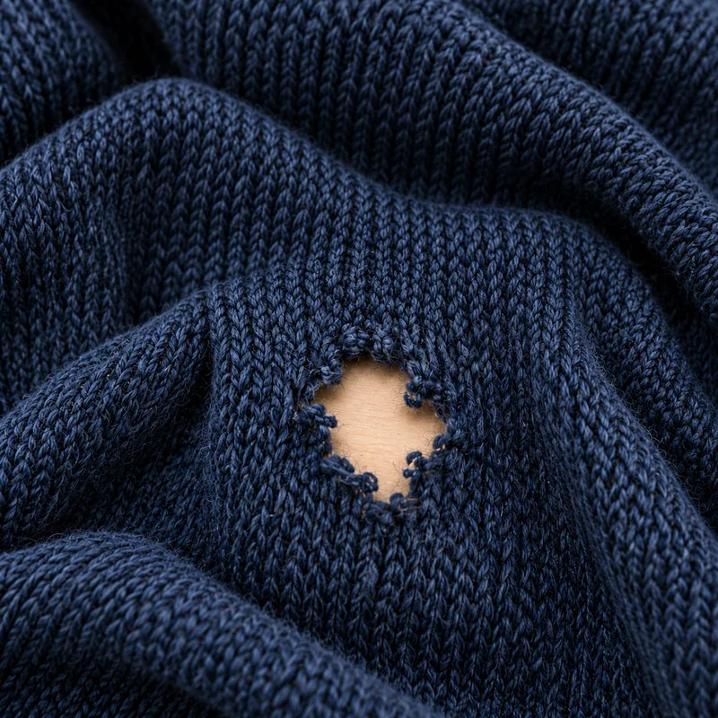 Trou dans une maille bleu marine, avant la reprise.